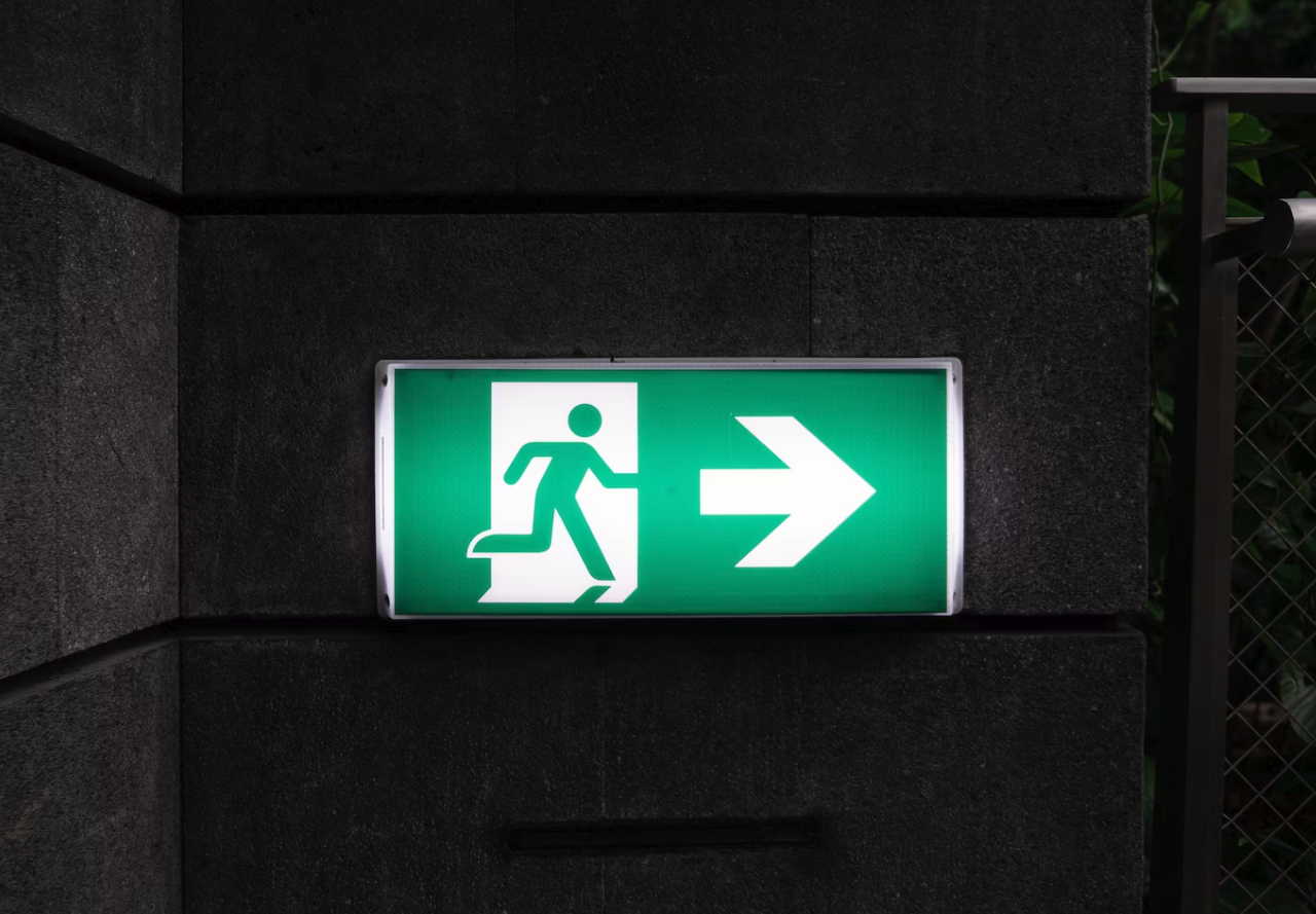 green emergency exit sign in dark room